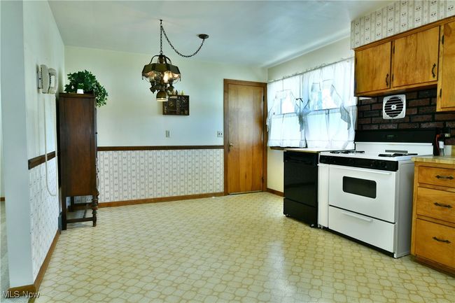Kitchen with gas range gas stove, baseboards, wallpapered walls, brown cabinets, and dishwasher | Image 15