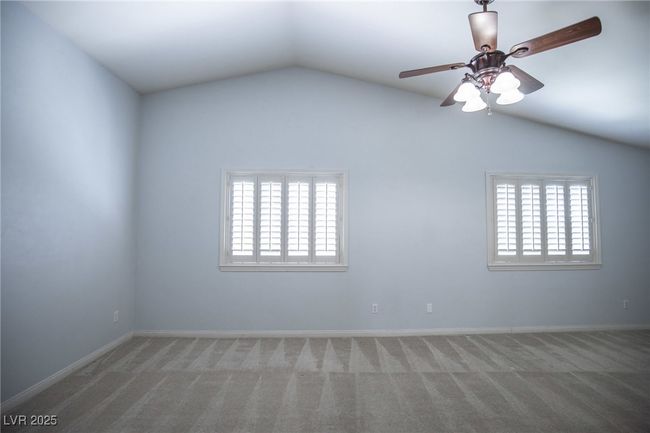 Empty room with carpet, a ceiling fan, vaulted ceiling, and baseboards | Image 19