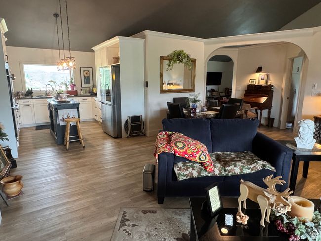 Living area featuring arched walkways, light wood-type flooring, lofted ceiling, and a chandelier | Image 4