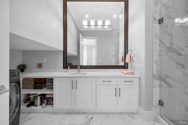 Bathroom with marble finish floors, a marble finish shower, vanity, and washer / dryer | Image 20