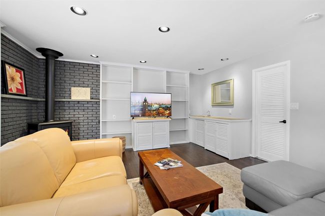 Living area with a wood stove, brick wall, dark wood-type flooring, and recessed lighting | Image 19