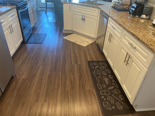 Kitchen featuring dark wood-type flooring, appliances with stainless steel finishes, white cabinetry, and light stone countertops | Image 14