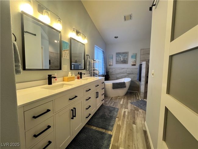 Bathroom featuring double vanity, wood finished floors, a freestanding bath, tile walls, and a wainscoted wall | Image 33