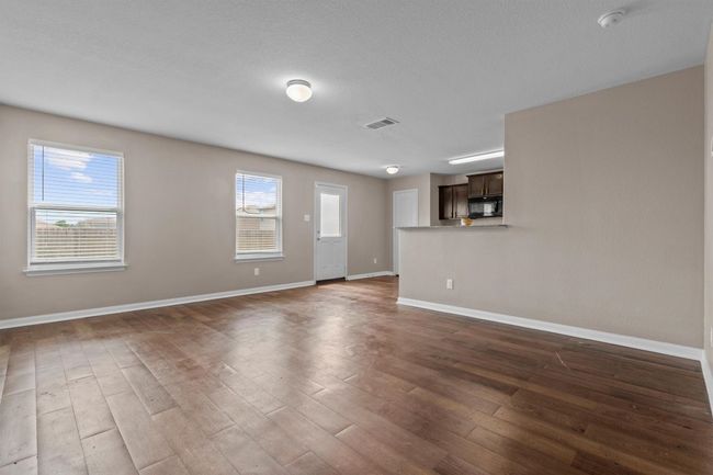 Unfurnished living room with visible vents, baseboards, a wealth of natural light, and hardwood / wood-style flooring | Image 4