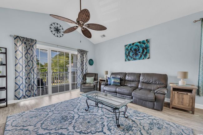 Living area featuring wood finished floors, visible vents, high vaulted ceiling, and ceiling fan | Image 14