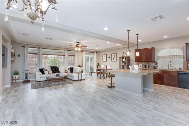 Kitchen featuring light wood finished floors, open floor plan, visible vents, and black dishwasher | Image 9