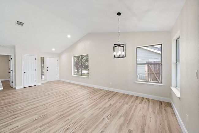 Unfurnished living room featuring light wood-style floors, lofted ceiling, a chandelier, and recessed lighting | Image 10