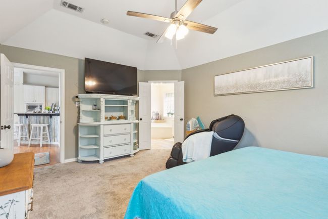 Bedroom with carpet floors, connected bathroom, vaulted ceiling, and visible vents | Image 18