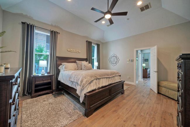 Bedroom featuring light wood finished floors, multiple windows, vaulted ceiling, and visible vents | Image 17