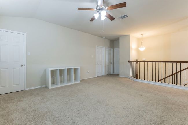 Carpeted spare room with vaulted ceiling, baseboards, a ceiling fan, and visible vents | Image 22