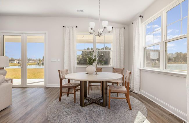 Dining area with baseboards, a chandelier, wood finished floors, lofted ceiling, and a water view | Image 15