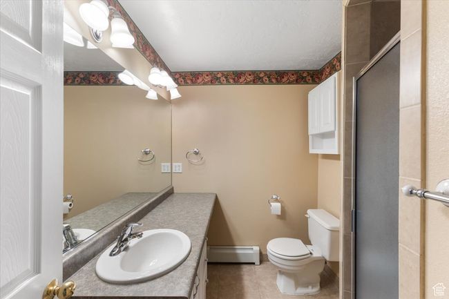 Full bathroom with vanity, a baseboard heating unit, tile patterned flooring, an enclosed shower, and toilet | Image 22