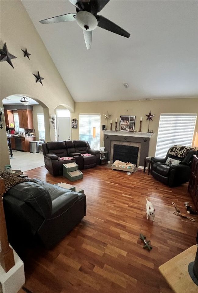 Living area featuring arched walkways, wood finished floors, a ceiling fan, a fireplace, and vaulted ceiling | Image 7