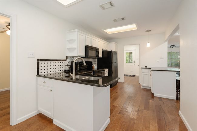 Kitchen with black appliances, dark countertops, open shelves, and a ceiling fan | Image 14