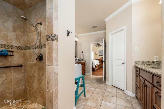 Full bath featuring a tile shower, ornamental molding, ceiling fan, vanity, and ensuite bath | Image 24