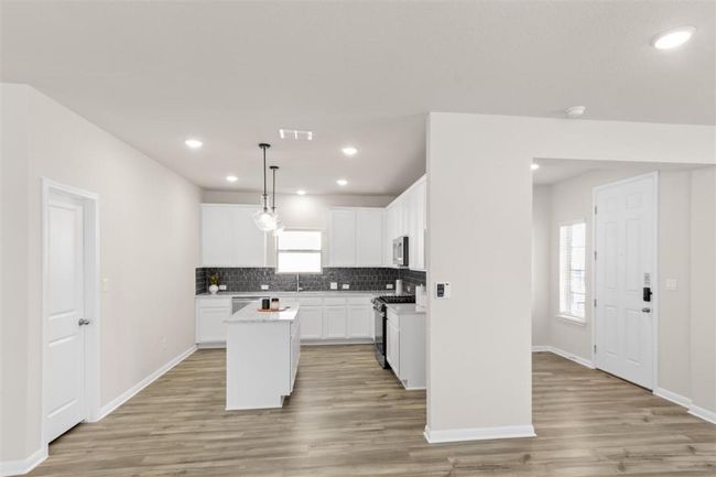 Kitchen featuring light countertops, backsplash, a kitchen island, stainless steel appliances, and visible vents | Image 14