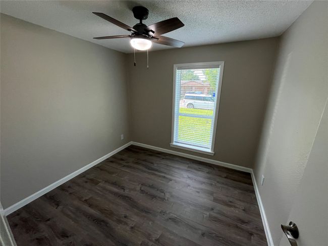 Unfurnished room with dark wood-style floors, a textured ceiling, baseboards, and ceiling fan | Image 14