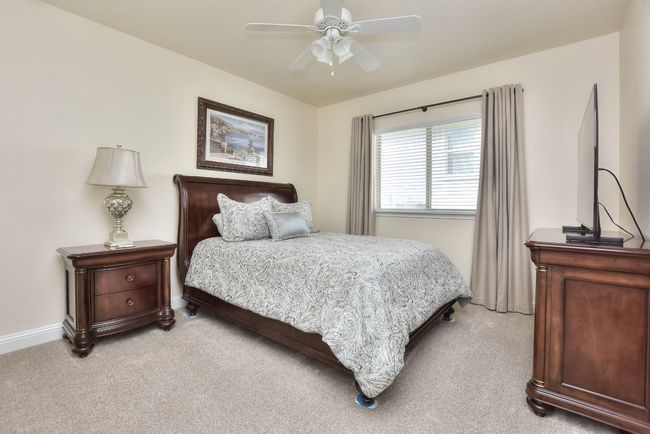 Bedroom with light colored carpet, baseboards, and ceiling fan | Image 17