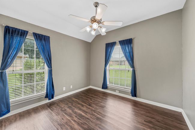 Empty room with healthy amount of natural light, ceiling fan, wood finished floors, and vaulted ceiling | Image 11