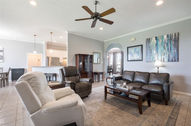 Living area with arched walkways, recessed lighting, a ceiling fan, crown molding, and light tile patterned flooring | Image 8