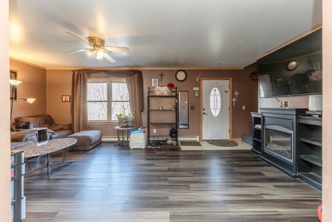 Living area with a wealth of natural light, a baseboard heating unit, a ceiling fan, and wood finished floors | Image 5