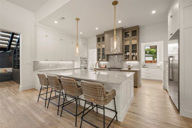 Large island seats 4, floor to ceiling cabinetry, gas range top, pendant lighting convection ovens. | Image 9