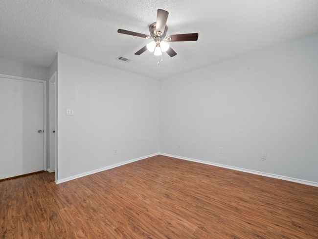 Empty room with wood finished floors, a ceiling fan, and a textured ceiling | Image 9