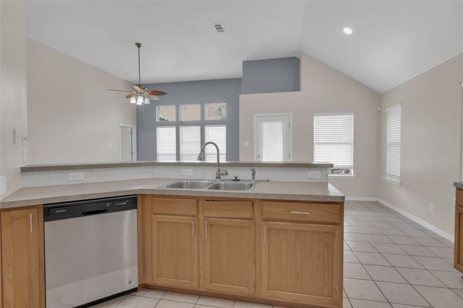 Kitchen featuring dishwasher, a ceiling fan, light tile patterned floors, vaulted ceiling, and light countertops | Image 17