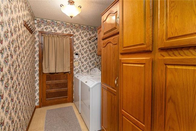 Laundry room with independent washer and dryer, wallpapered walls, cabinet space, and a textured ceiling | Image 12