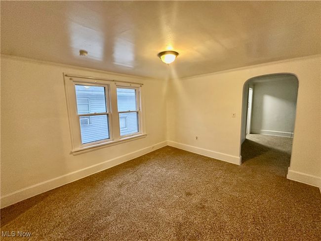 Spare room with arched walkways, crown molding, dark colored carpet, and baseboards | Image 12