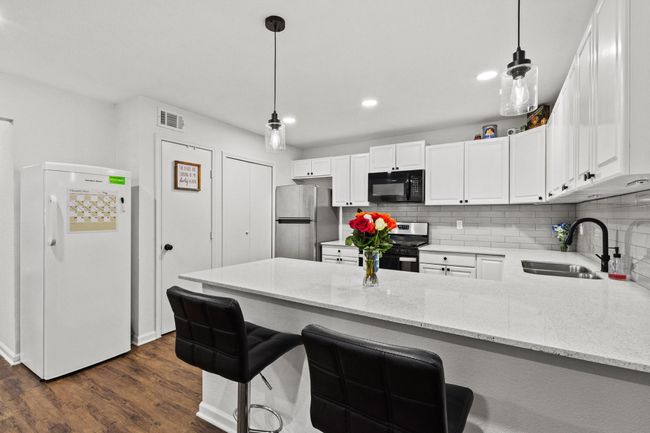 Kitchen with stainless steel appliances, a sink, a peninsula, white cabinets, and recessed lighting | Image 8