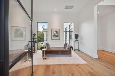 This grand entryway, framed by sleek steel windows and a striking front door, offers a stunning view of the expansive back lawn. The wide, open space provides the perfect setting to showcase impressive artwork, making a bold first impression. To the left, you'll find the first-floor study, creating a seamless blend of elegance and functionality. | Image 3