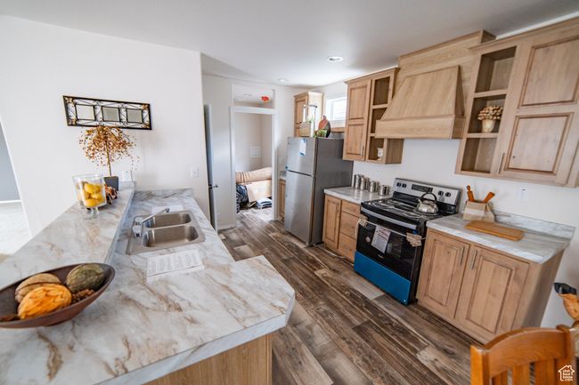 Kitchen with a sink, appliances with stainless steel finishes, light countertops, custom range hood, and dark wood-style flooring | Image 59