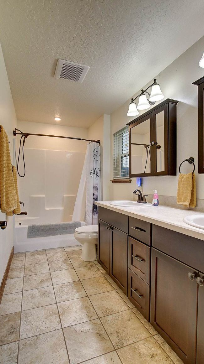 Full bathroom featuring a textured ceiling, toilet, vanity, shower / tub combo, and tile patterned flooring | Image 21