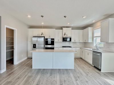 Expansive, timeless, white kitchen with refrigerator, double ovens, gas cooktop, microwave vented to outside, and soft close doors and drawers. | Image 2