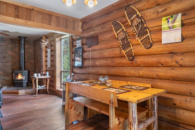 Dining space with log walls, a wood stove, and wood finished floors | Image 41
