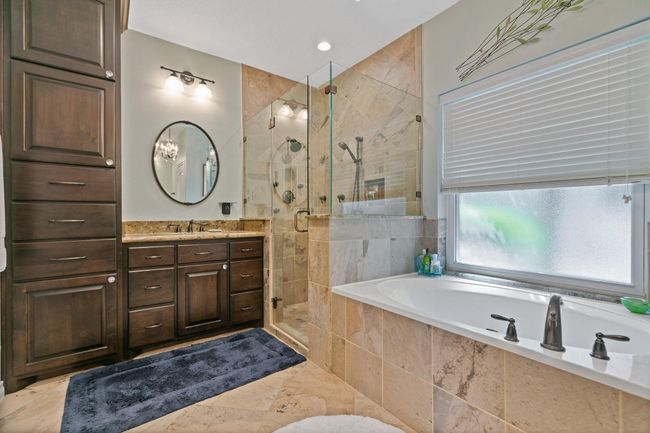 Custom-made rich wood cabinetry with abundant storage and a convenient built-in laundry hamper makes getting ready a breeze. | Image 19