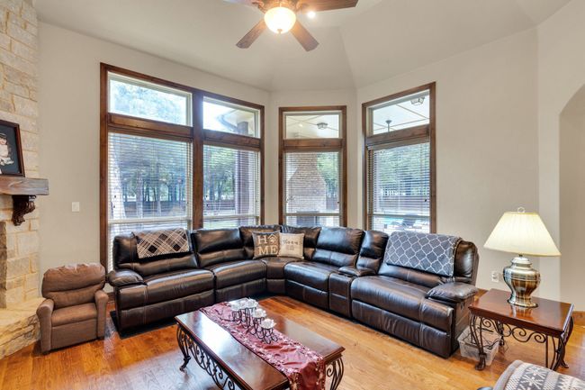 Living area with healthy amount of natural light, a ceiling fan, wood finished floors, and a fireplace | Image 16