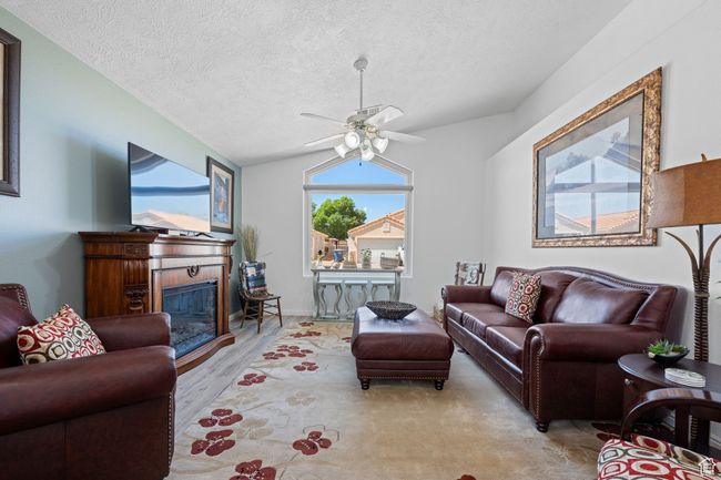 Living room featuring a textured ceiling, ceiling fan, and a glass covered fireplace | Image 5