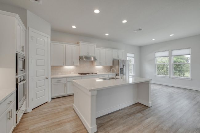 Kitchen featuring a kitchen island with sink, light countertops, tasteful backsplash, light wood-style floors, and recessed lighting | Image 10