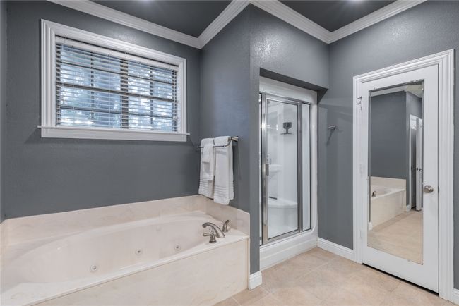 Bathroom featuring a stall shower, a whirlpool tub, crown molding, and tile patterned flooring | Image 20