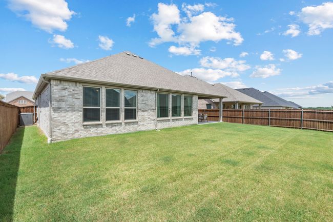 Back of property featuring a fenced backyard, roof with shingles, brick siding, and a patio | Image 33