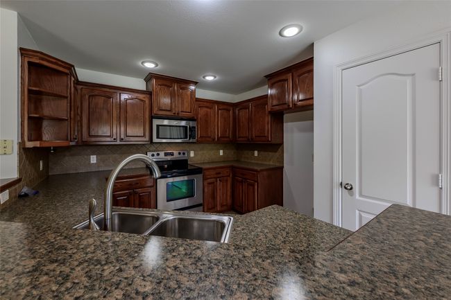 Kitchen featuring open shelves, tasteful backsplash, stainless steel appliances, and a sink | Image 17