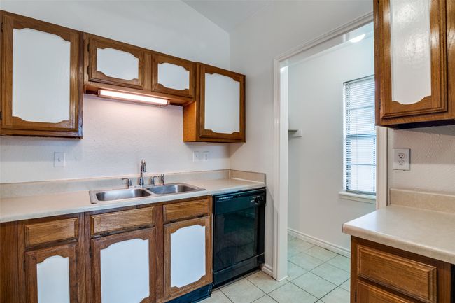 Kitchen featuring black dishwasher, light tile patterned flooring, and light countertops | Image 14