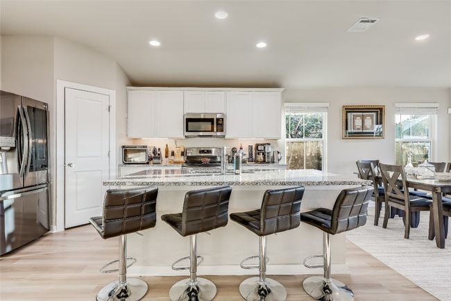 Kitchen with stainless steel appliances, light wood-style floors, light stone counters, plenty of natural light, and recessed lighting | Image 10