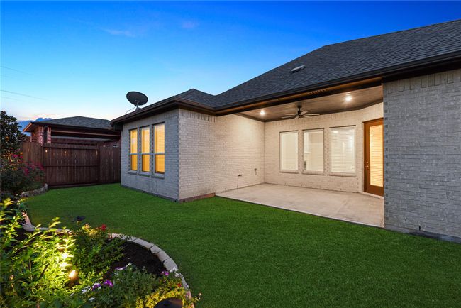 This spacious covered patio offers the perfect setting to enjoy morning coffee, a nightcap with your favorite person, and everything in between. With soft lighting, a ceiling fan, and views of the beautifully landscaped yard, it's an inviting space for relaxation any time of day. | Image 37