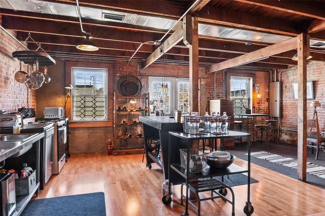 Kitchen with gas stove, beam ceiling, brick wall, and wood finished floors | Image 18