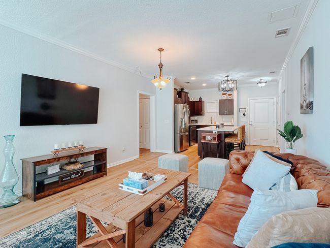 Living area with visible vents, ornamental molding, light wood-style flooring, and baseboards | Image 13