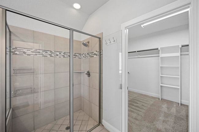 Bathroom featuring a shower stall, a walk in closet, and lofted ceiling | Image 32