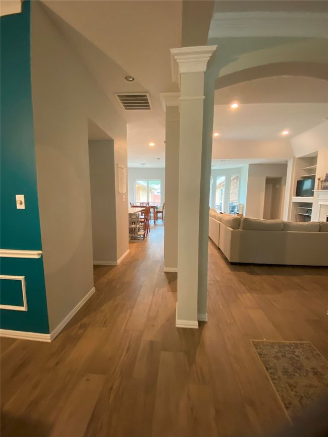Corridor with hardwood / wood-style flooring, baseboards, ornate columns, and visible vents | Image 7